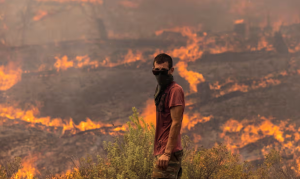 유럽 전역을 덮친 열파 사태 와중에 그리스 로도스 섬에선 지난 18일부터 산불이 발생해 강한 바람을 타고 확산하고 있다. 27일 한 남자가 그리스 로도스 섬의 아폴리나에서 산비탈을 삼키고 있는 화염과 싸울 준비를 하고 서 있다. : RondaChurchill·AFP·Getty Images